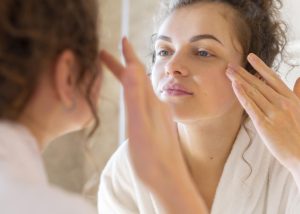 Woman applying glycolic acid while looking in the mirror