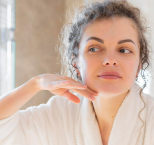 A woman staring happily to her face in the mirror 